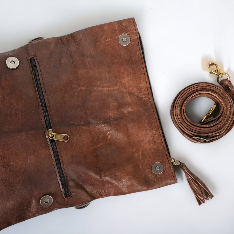 Brown leather clutch bag with strap on a white background