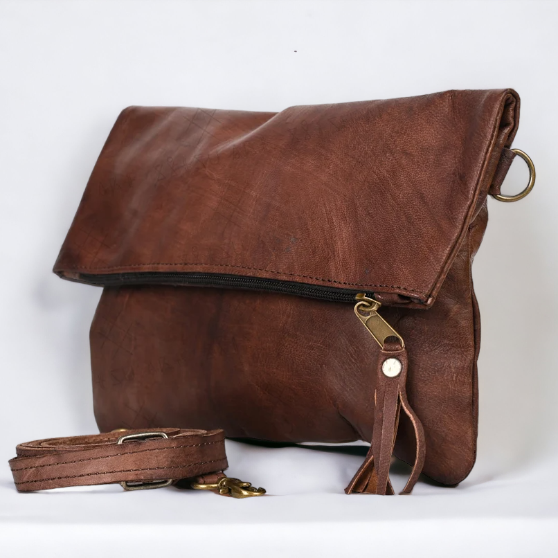 Brown leather bag with strap on a white background