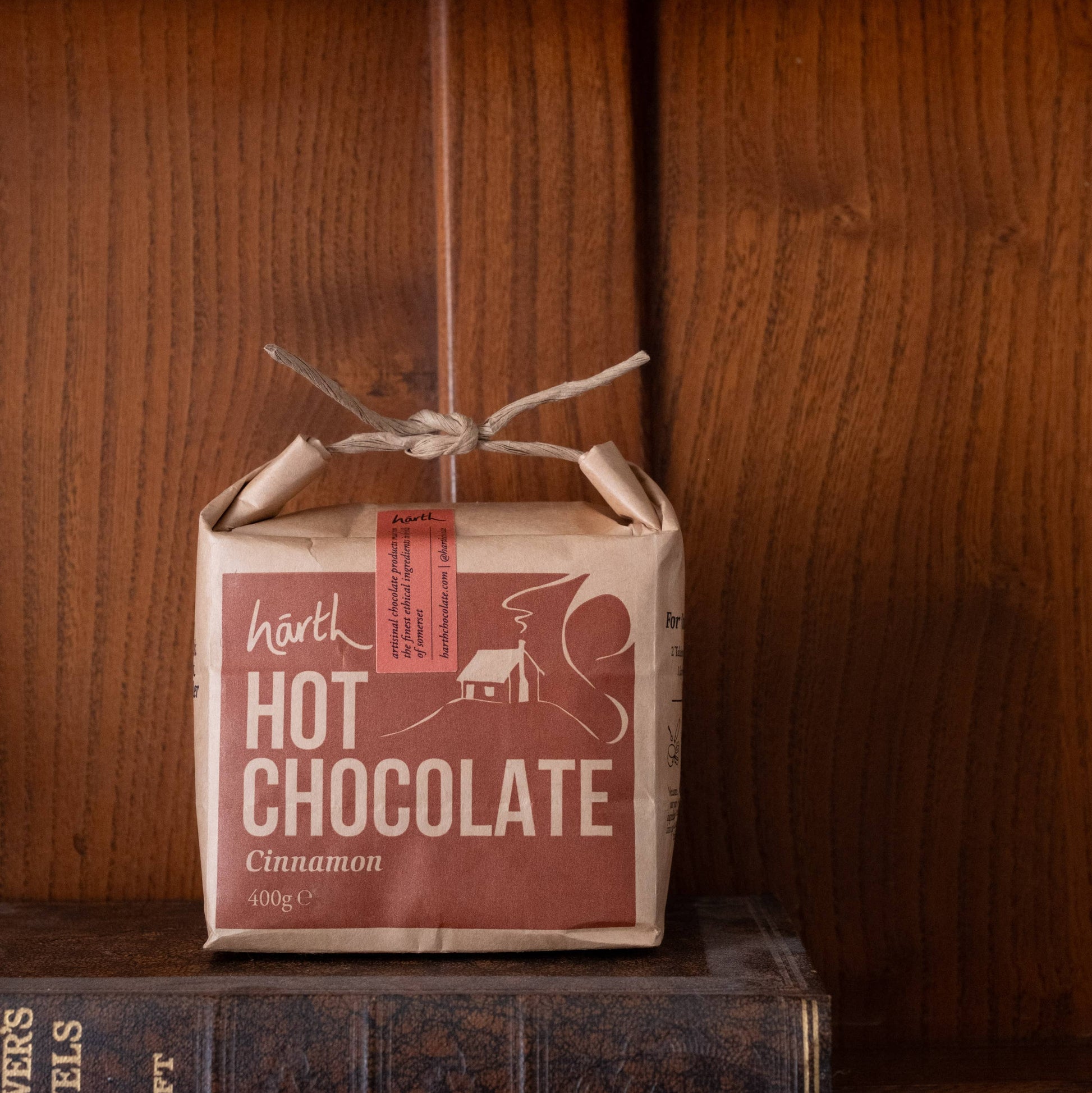 Box of Härth hot chocolate on a wooden shelf with a book below.
