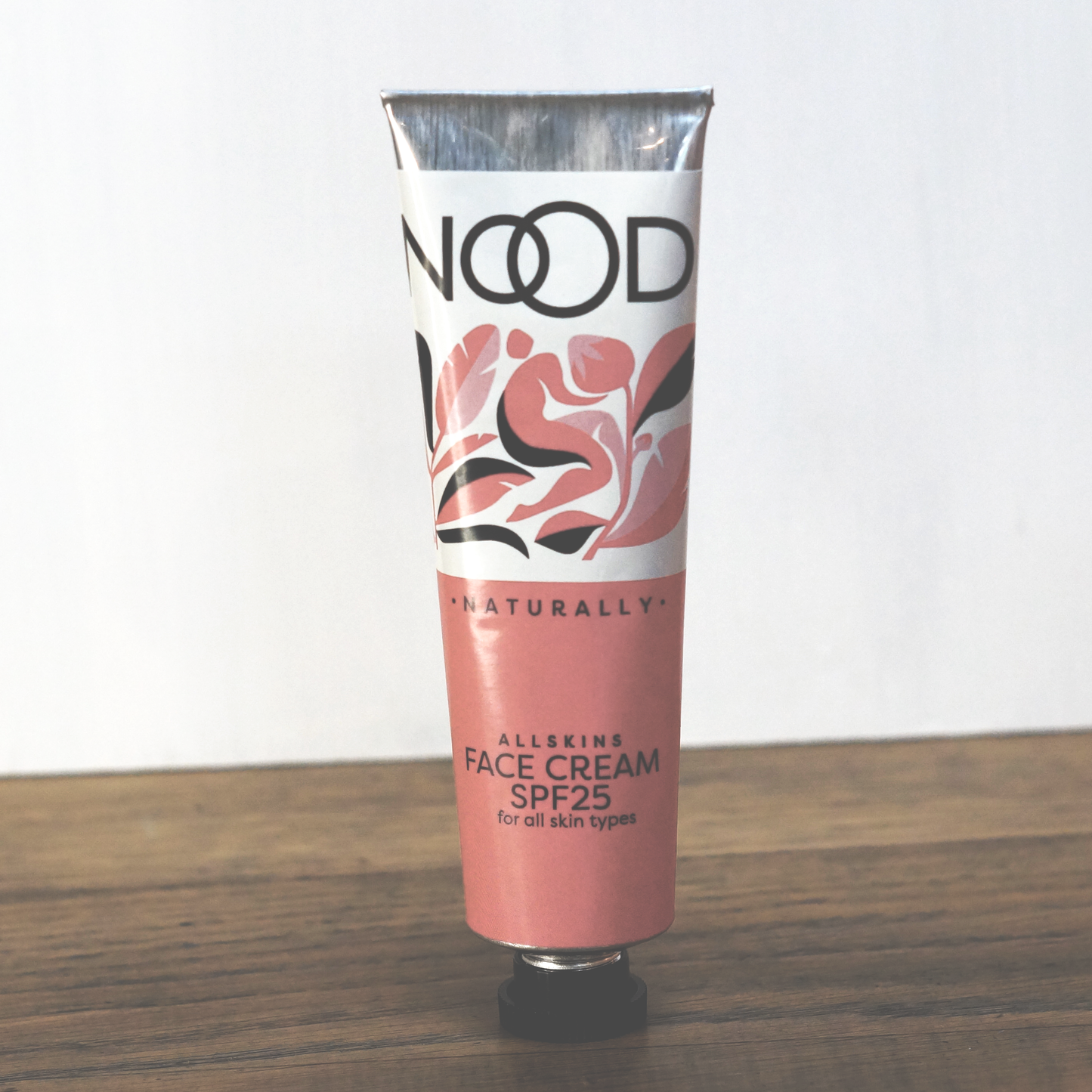 Aluminum tube of NOOD Allskins Face Cream with a floral pattern on the label, indicating SPF 25 and suitability for all skin types.