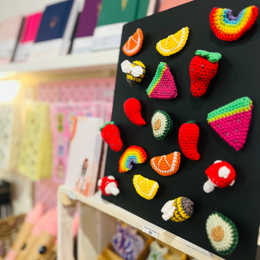 Colorful crochet magnets on a black board with a blurred background