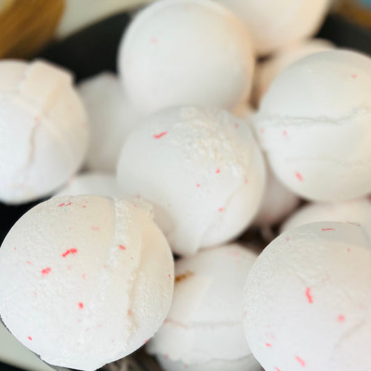 Multiple coconut dream bath bombs piled up. Each a bright white with small pink specs on them.
