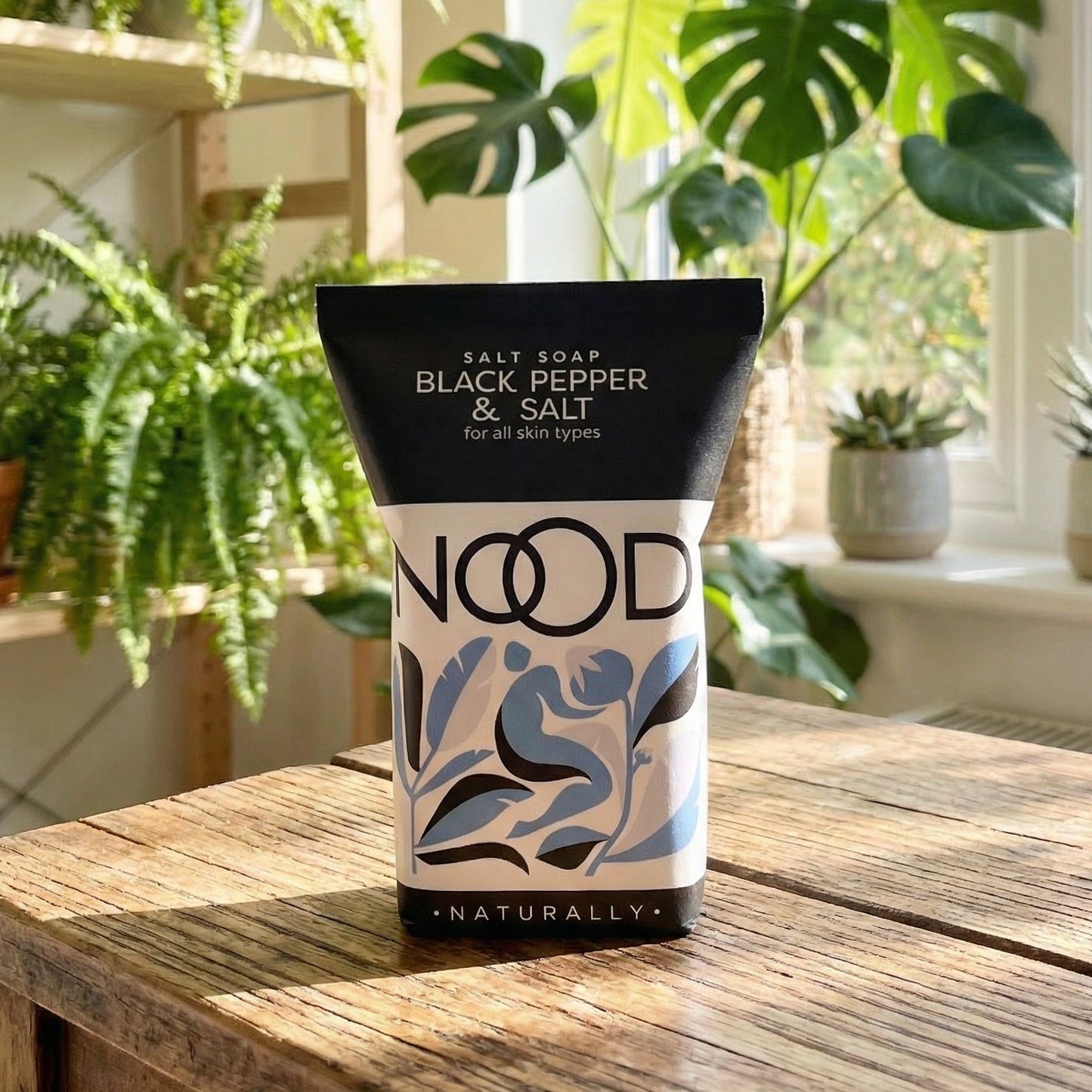 Nood product on a wooden table with plants in the background