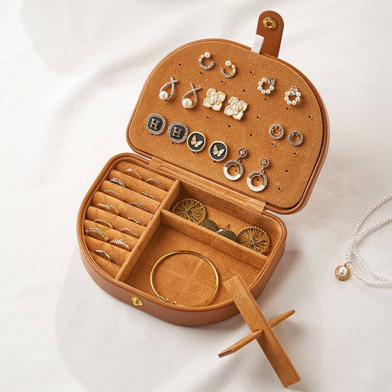 Brown jewelry box with various earrings and rings on a white background