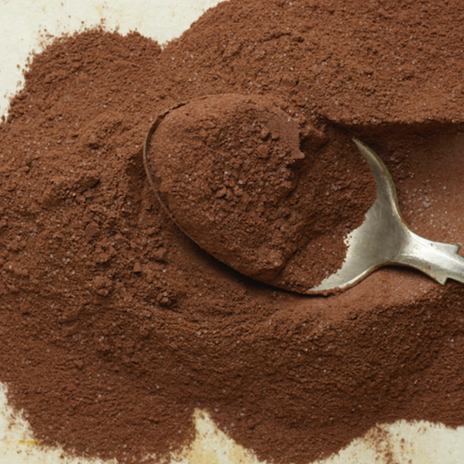 Cocoa powder with a metal scoop on a textured surface
