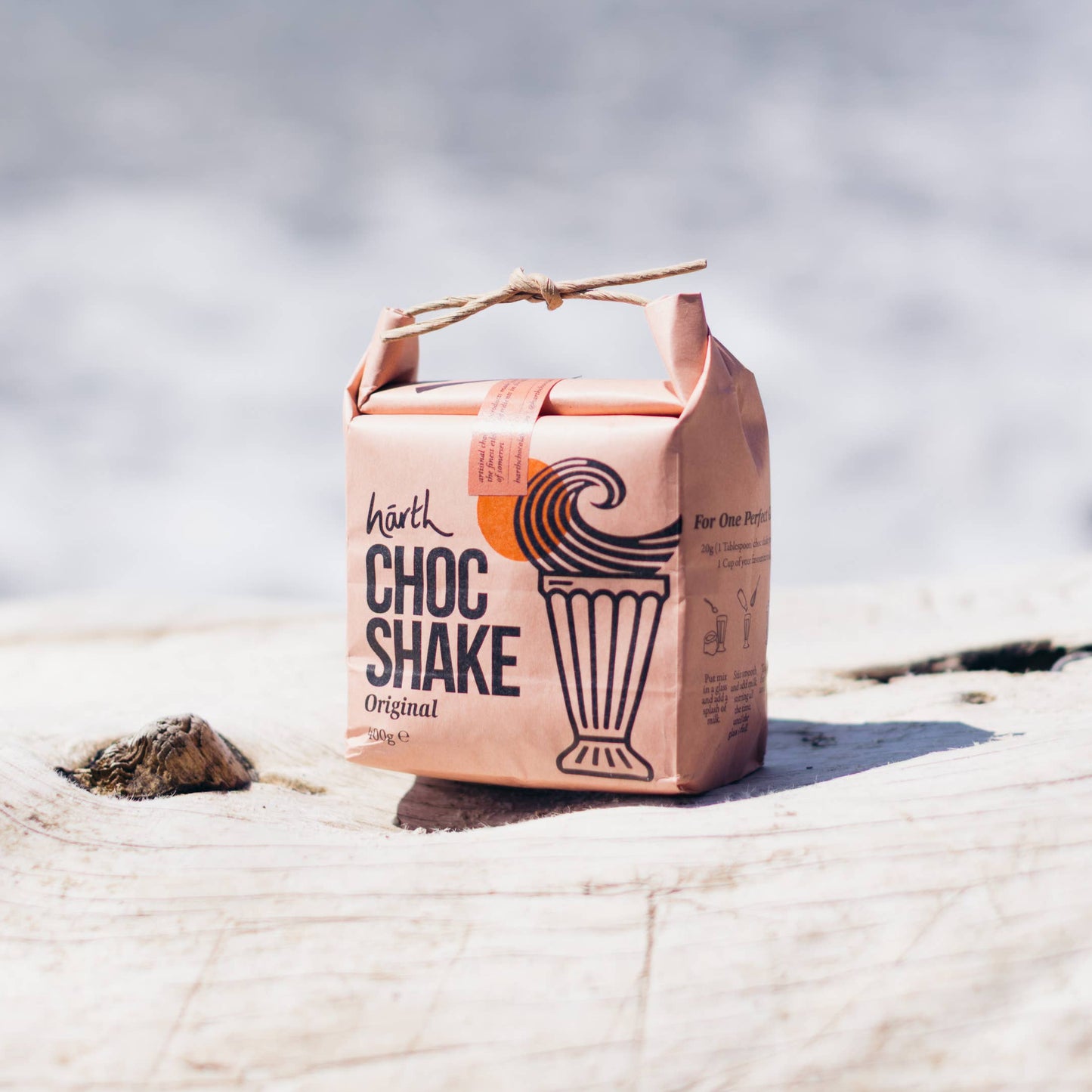 Carton of Choc Shake on a rock with water in the background
