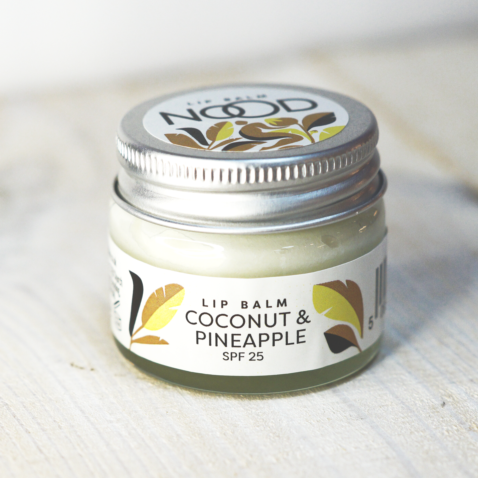 a small glass jar of coconut and pineapple lip balm, with an SPF of 25, made by NOOD Stores.