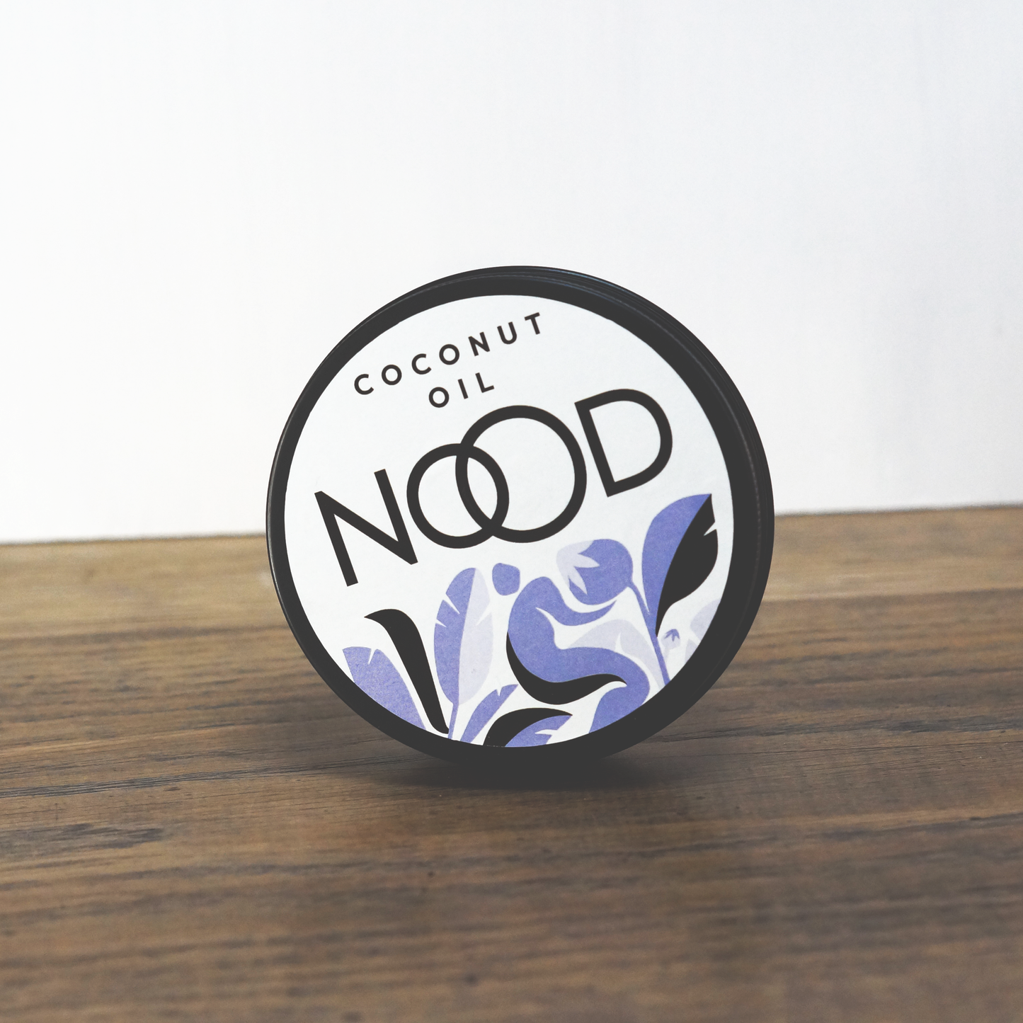 A black aluminium tin of coconut oil, made by NOOD Stores; the pachging is white, blue and black and has an abstract print on.