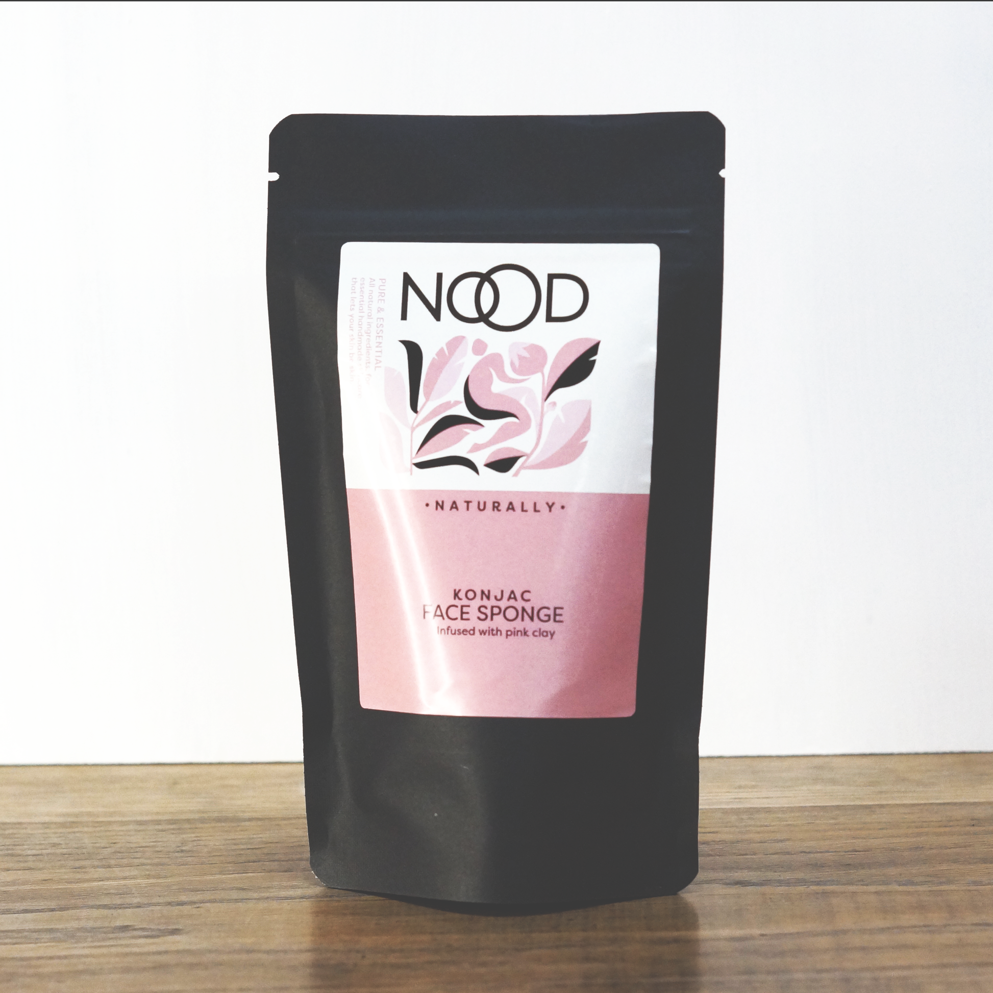 A nicely wrapped small black bag containing a Pink Clay Konjac Face Sponge from NOOD Stores.