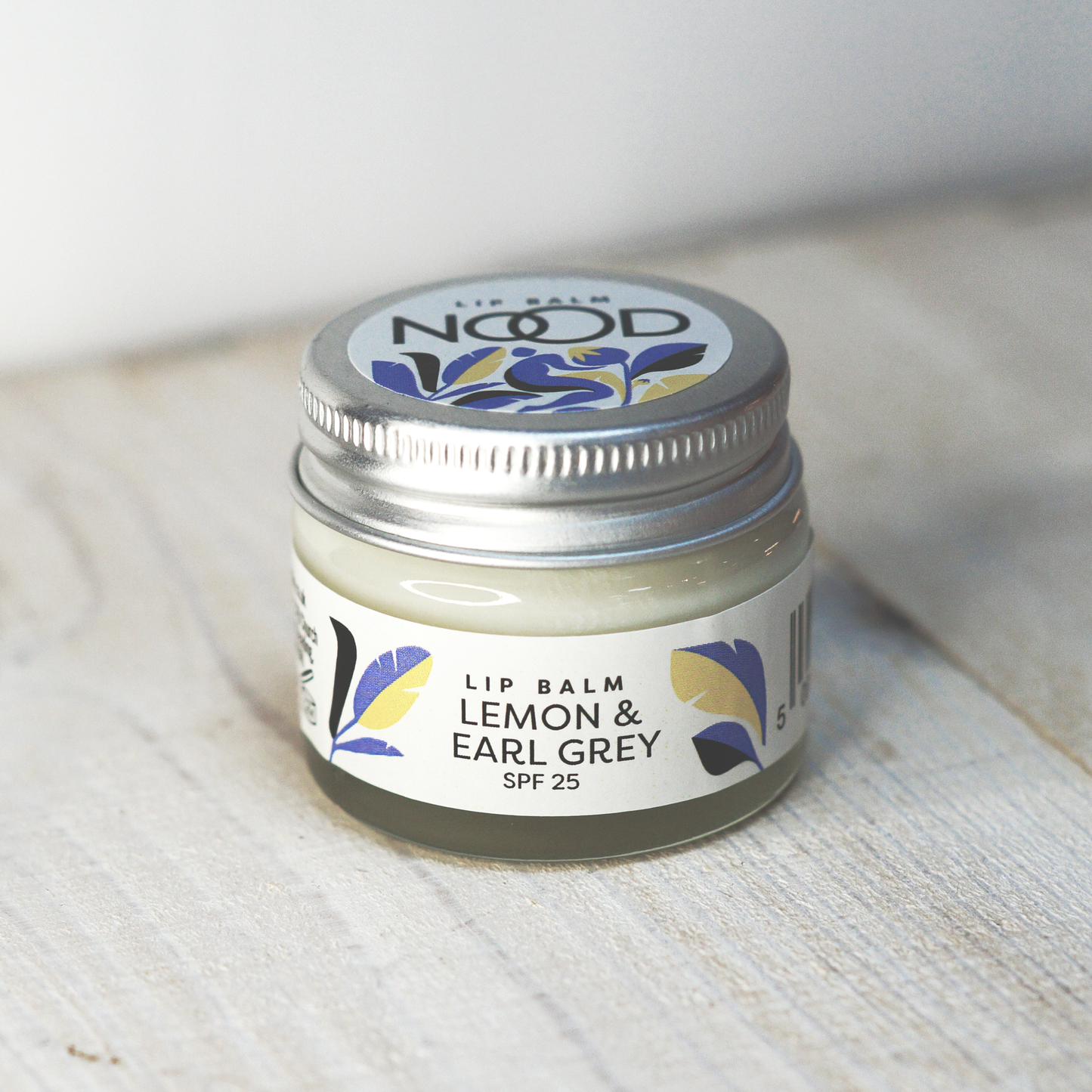 A glass jar of Lemon & Early Grey Lip balm, with an SPF of 25, created by NOOD Stores.