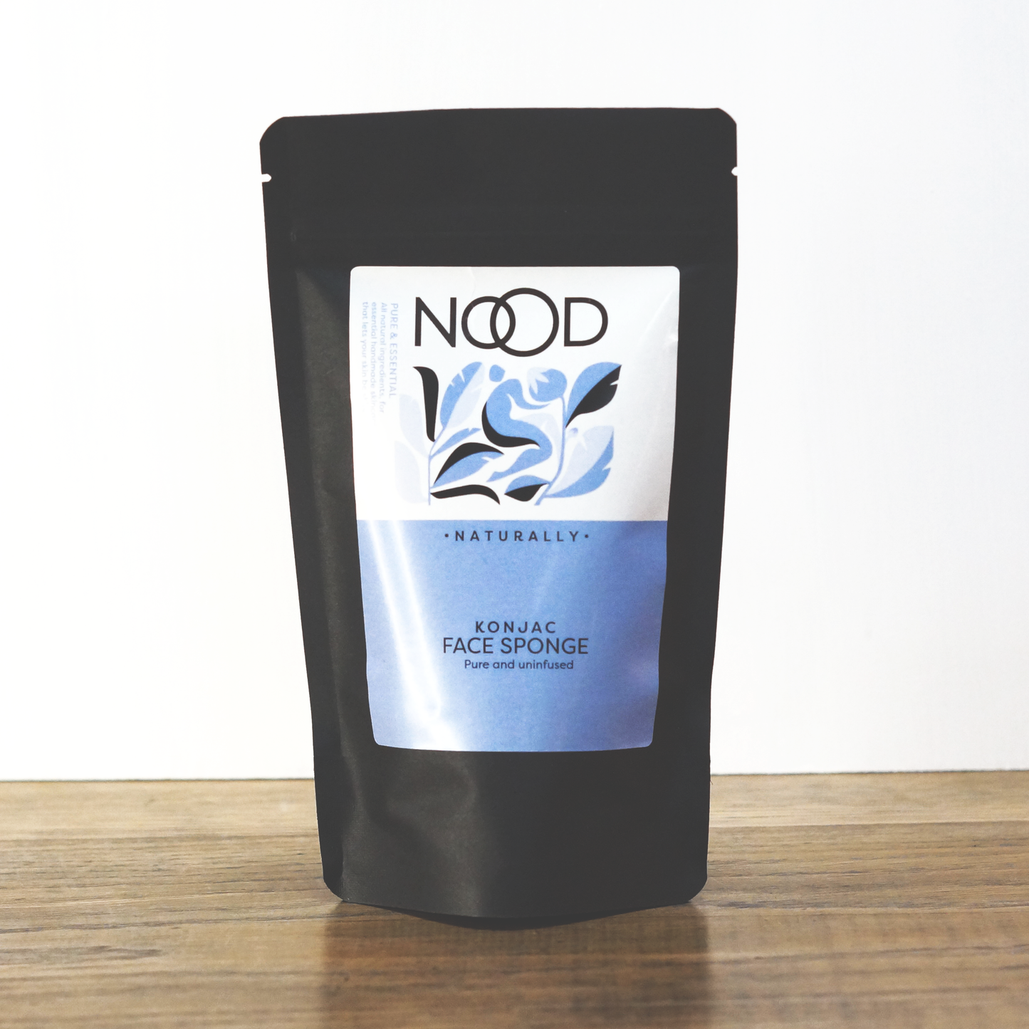A neatly packaged black bag from NOOD Stores that contains a natural Konjac Sponge.
