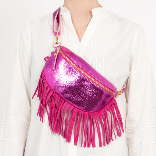 Pink metallic fringed bag worn by a person on a white background