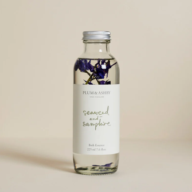 Bottle of Plum & Ashby bath essence with floral design on a beige background