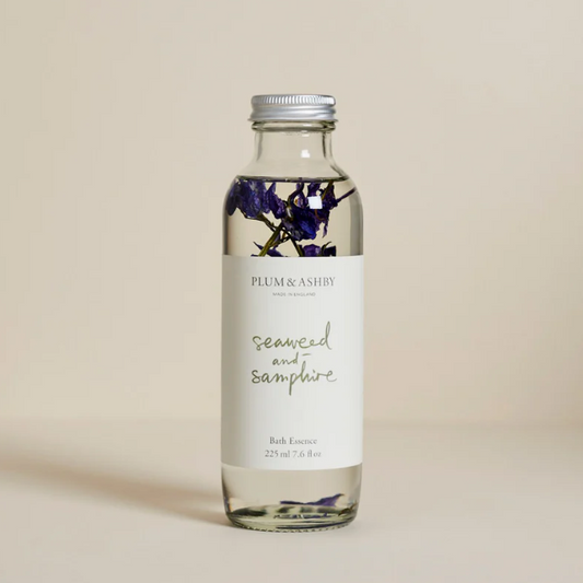Bottle of Plum & Ashby bath essence with floral design on a beige background
