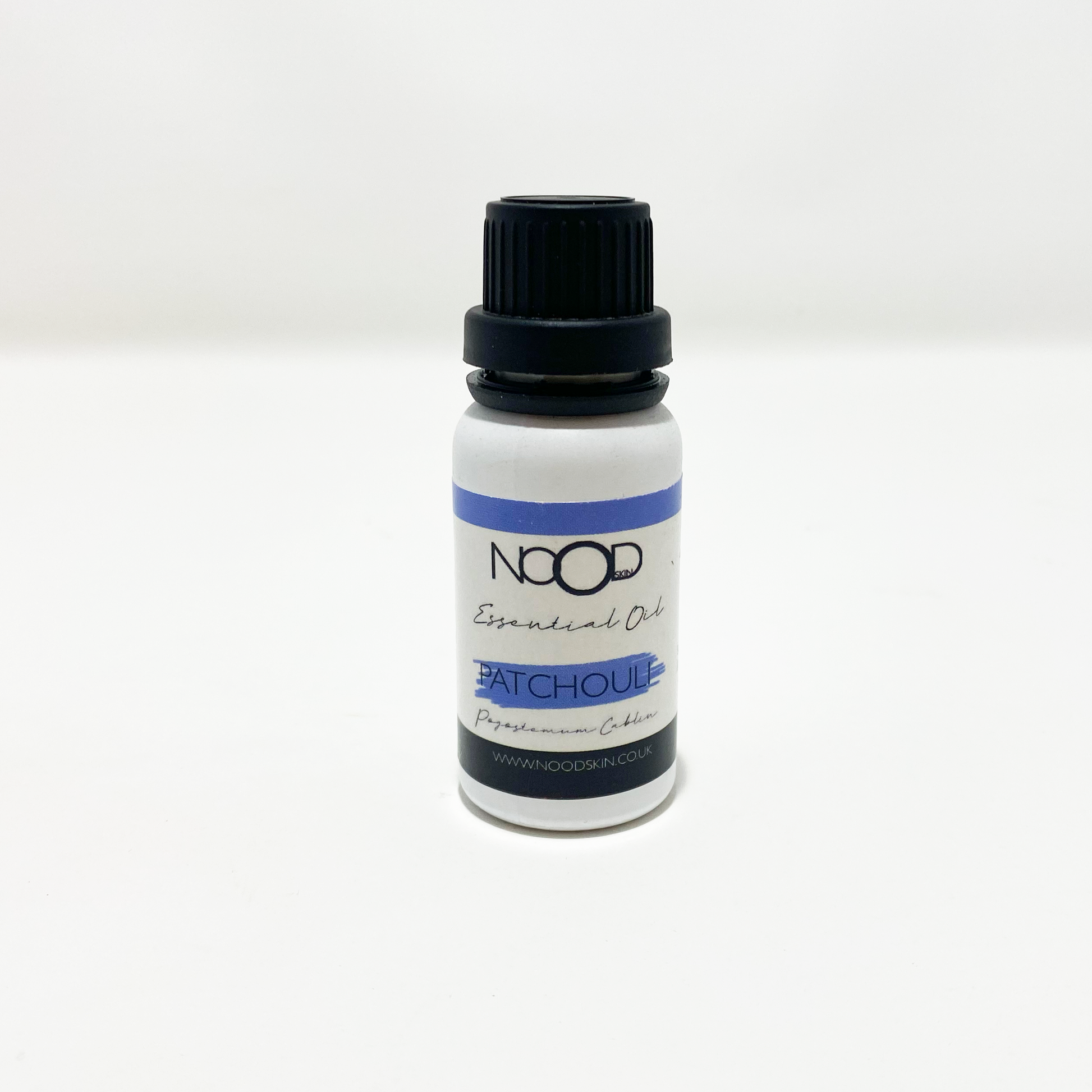 A small white bottle with a lack screw-top lid and a blue, white and black sticker that reads 'NOOD Skin' 'Essential Oil 'Patchouli' on it.