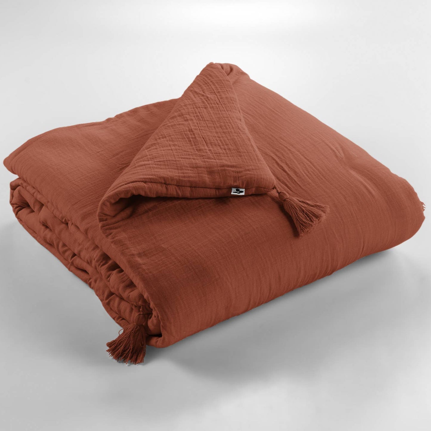 Folded terracotta-colored blanket on a light gray background
