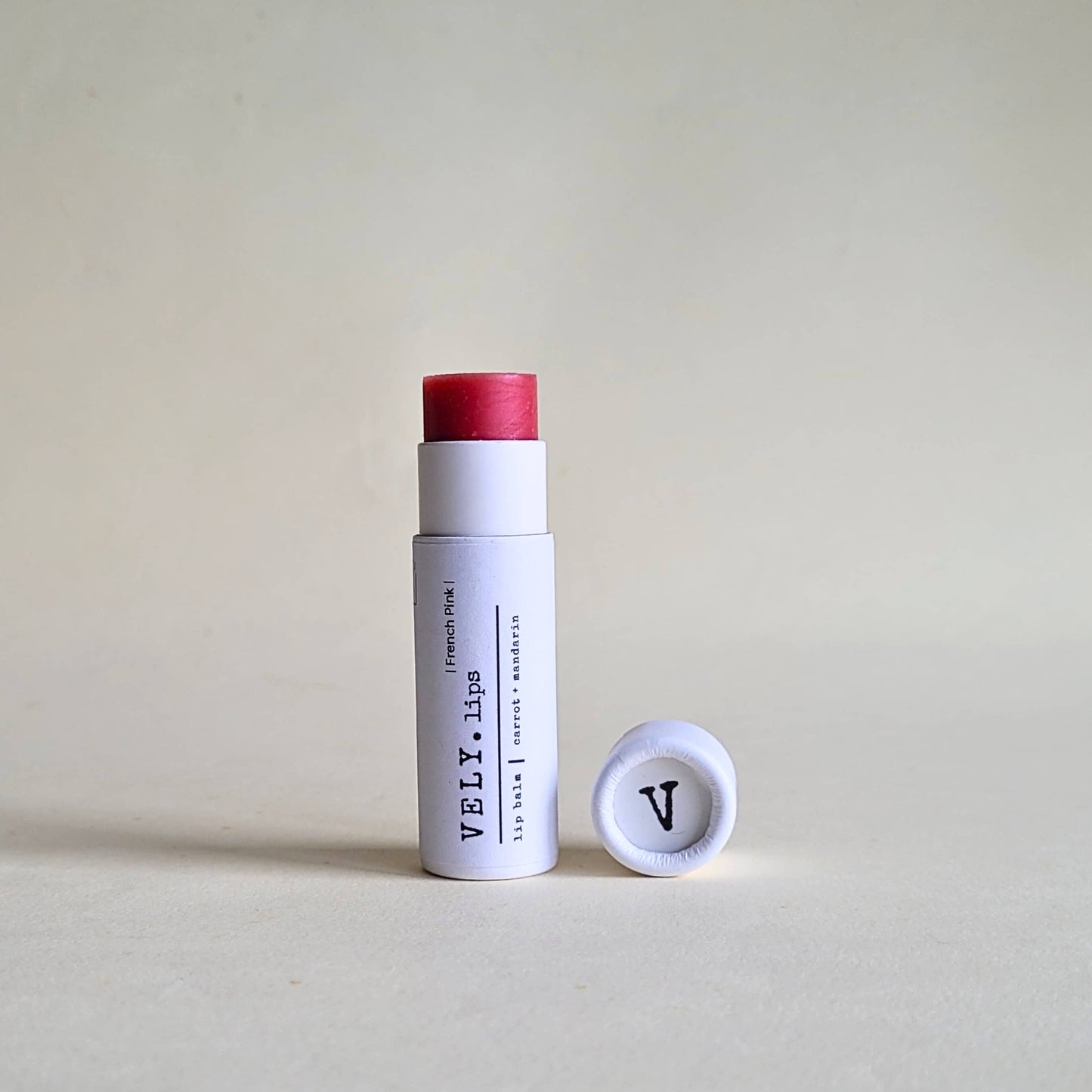 White cylindrical product with red cap and visible branding on a beige background