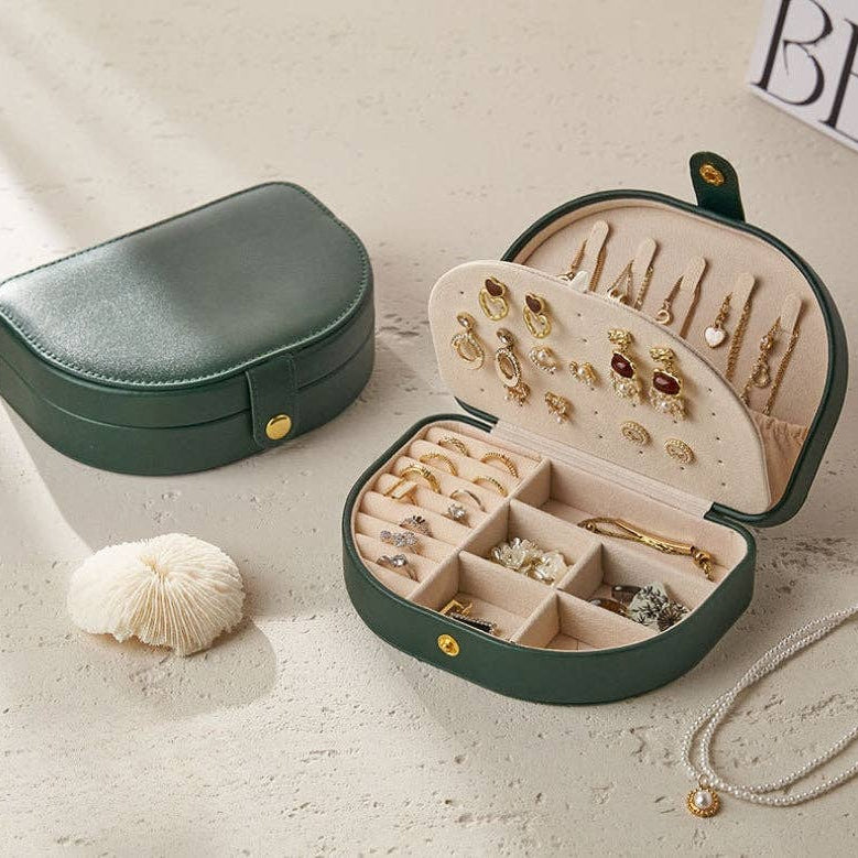 Green jewelry case with jewelry inside on a light surface