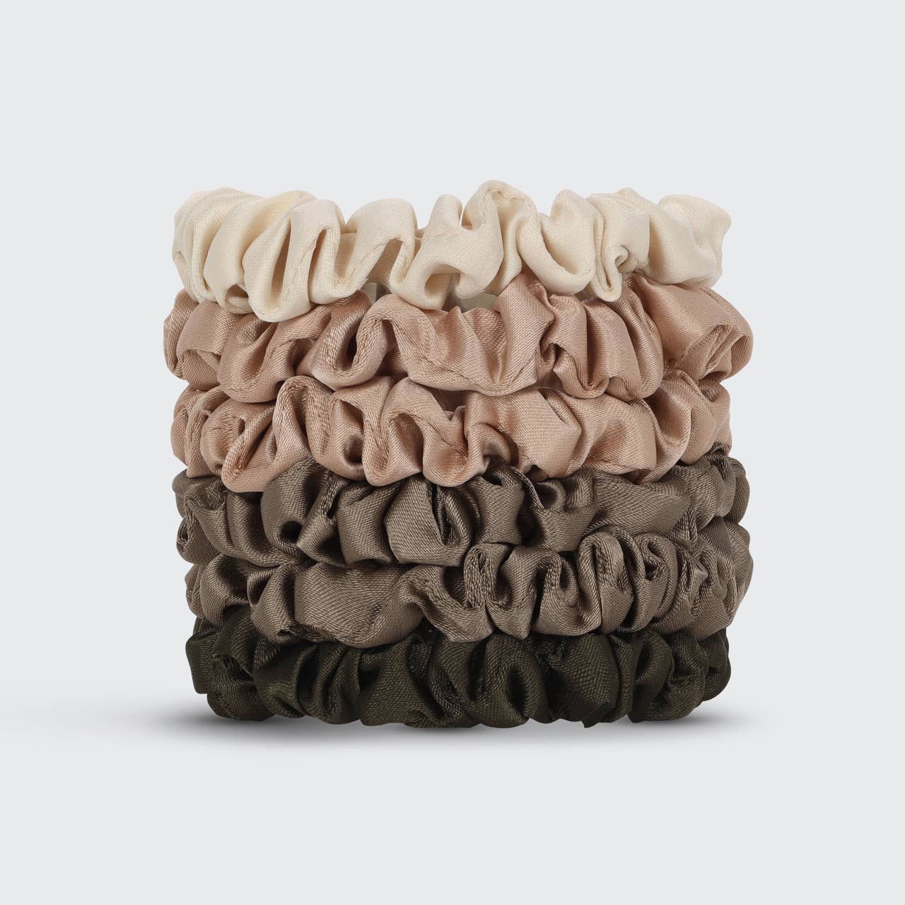 Stack of brown and beige scrunchies on a light gray background