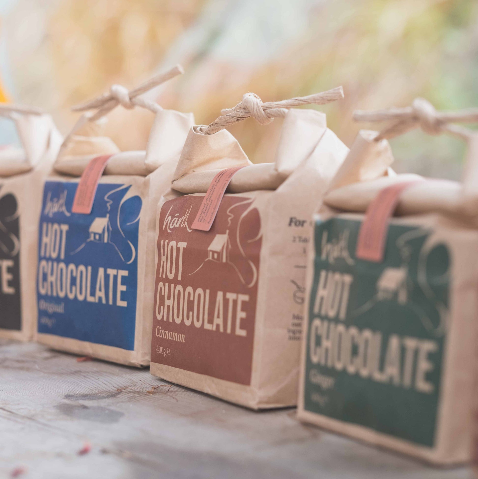 Three packages of hot chocolate with colorful labels on a wooden surface.
