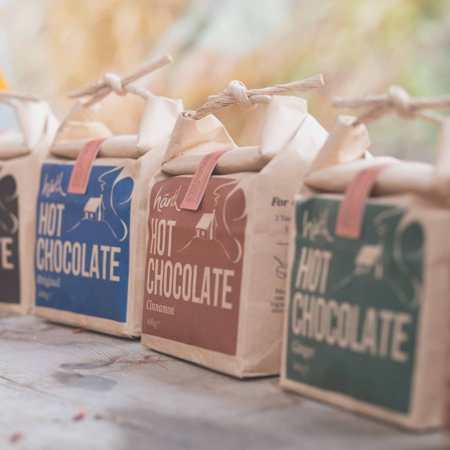 Three packages of hot chocolate with colorful labels on a wooden surface.