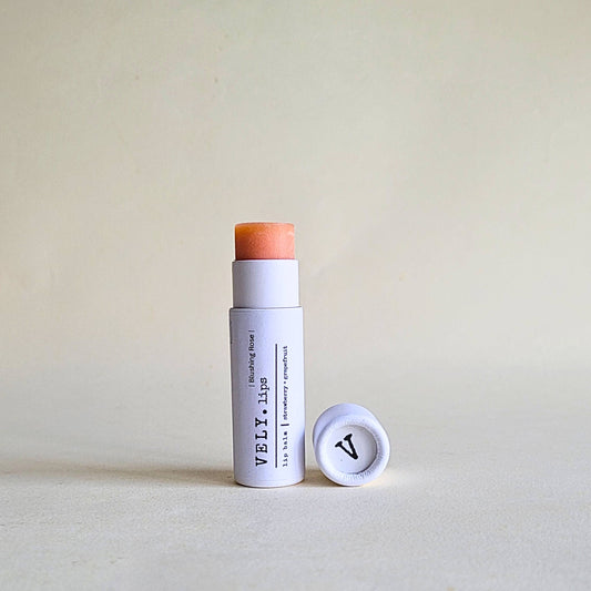 White lip balm with orange cap on a beige background