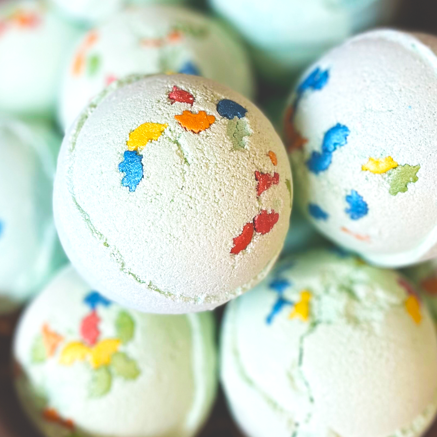 A bath bomb with green and blue colors, decorated with colorful pieces  on its surface.