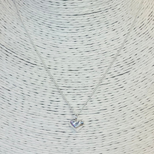 Silver heart-shaped pendant necklace on a textured beige background