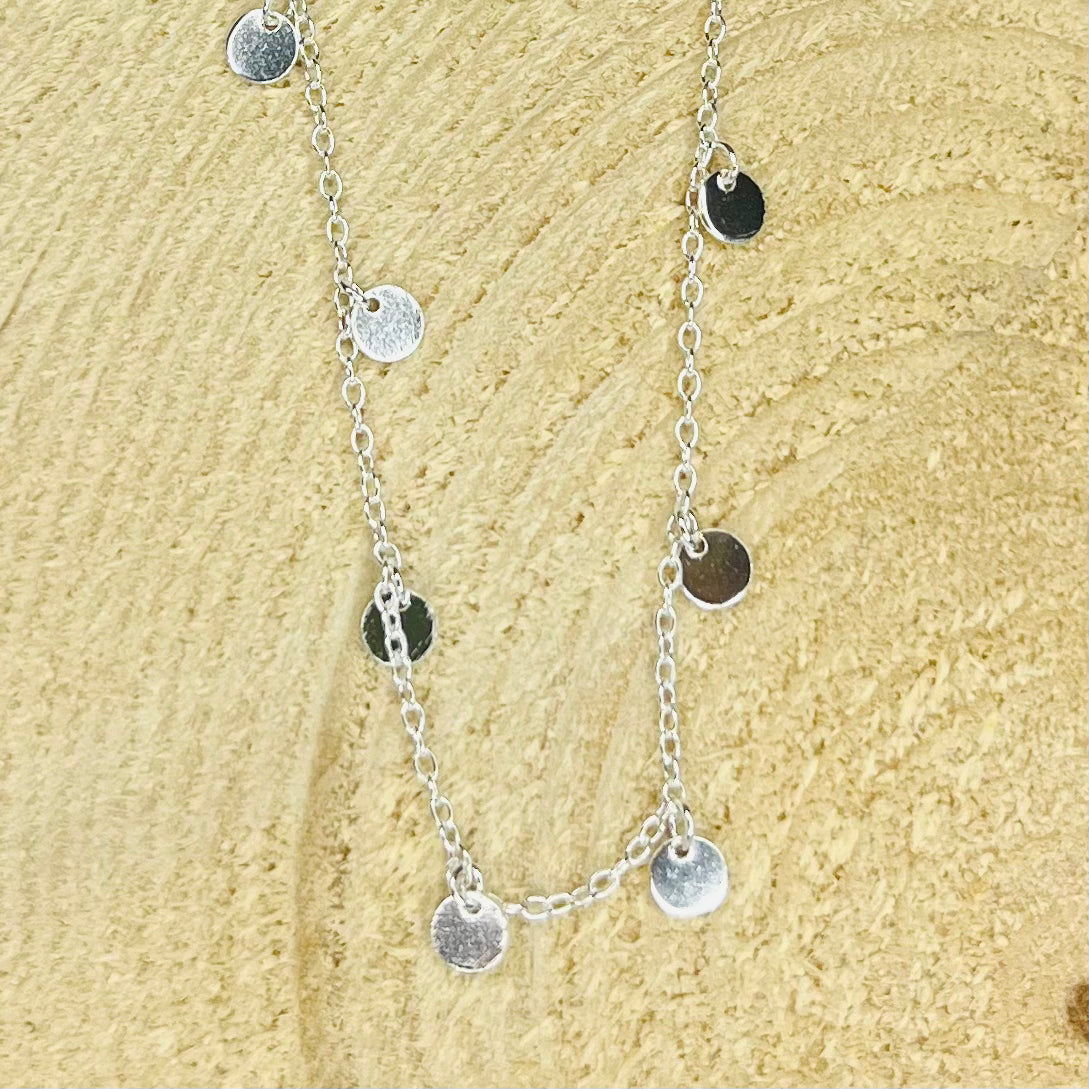 Silver necklace with round pendants on a beige textured background