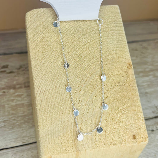 Silver necklace on a textured beige surface