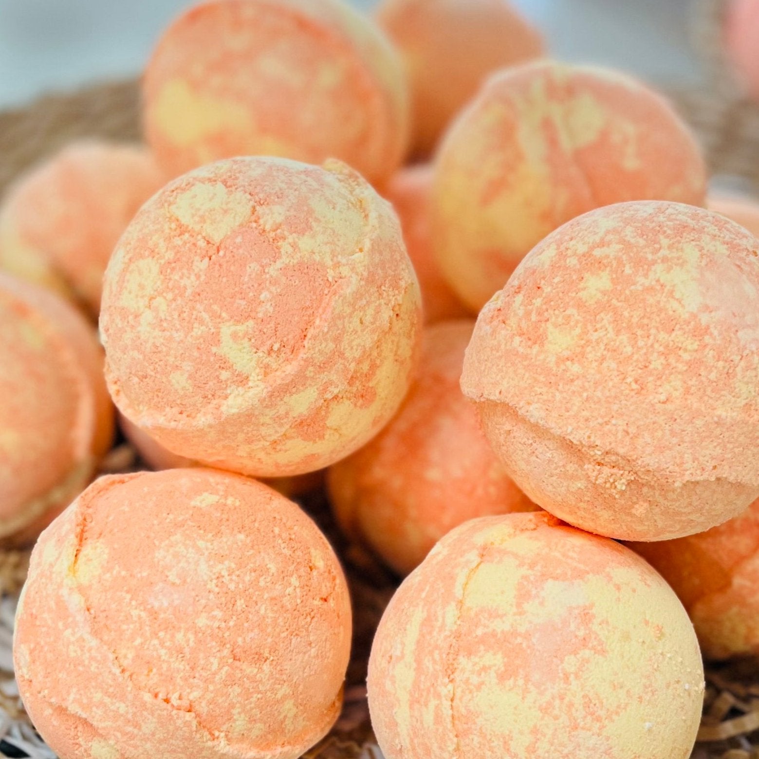 A collection of peach-colored bath bombs in various sizes, with a textured surface, displayed in a basket.