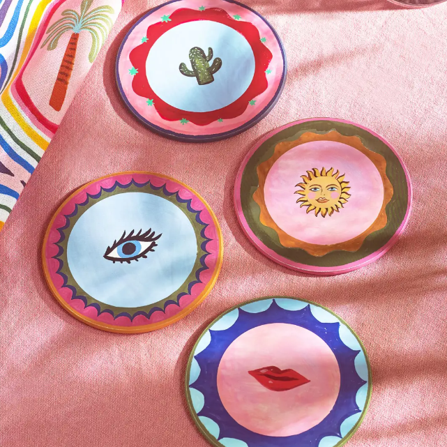 Set of colorful ceramic plates with artistic designs on a pink surface