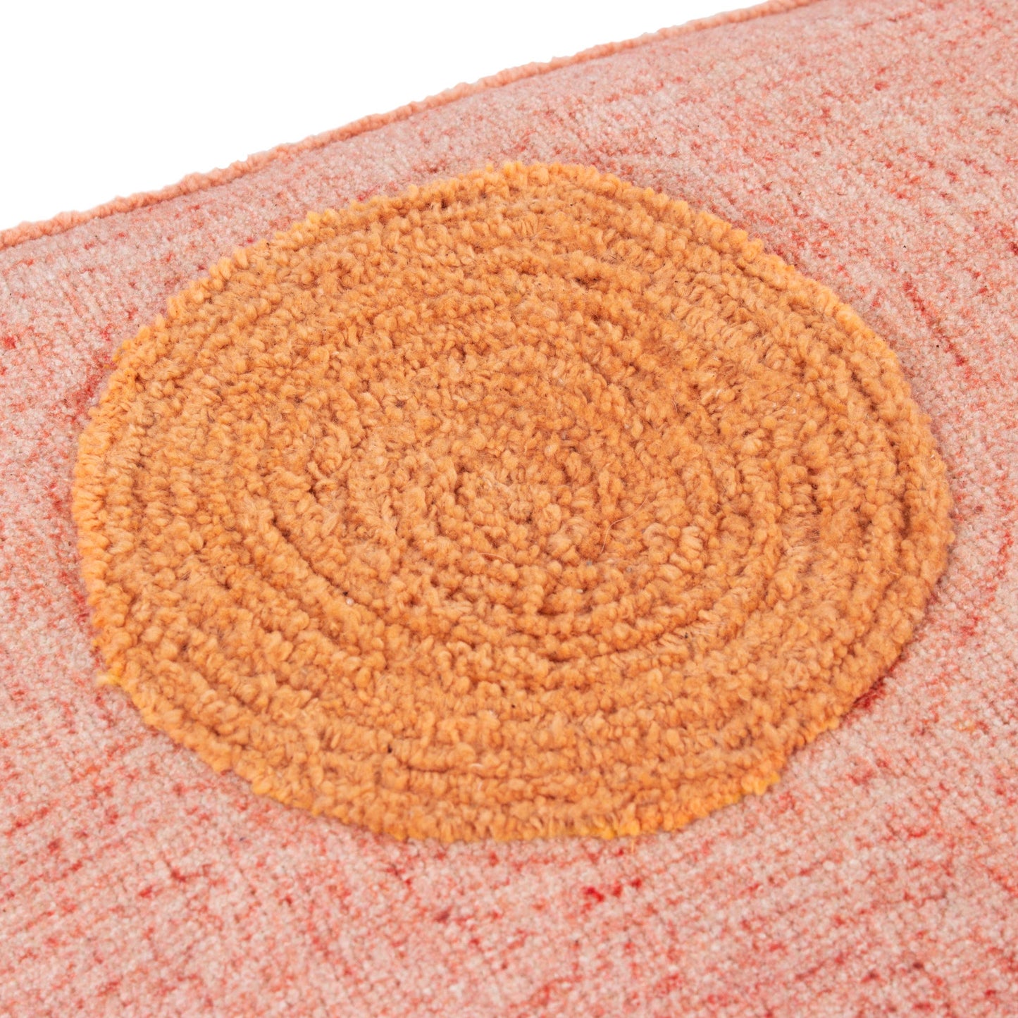 Round doormat with a textured surface on a pink background