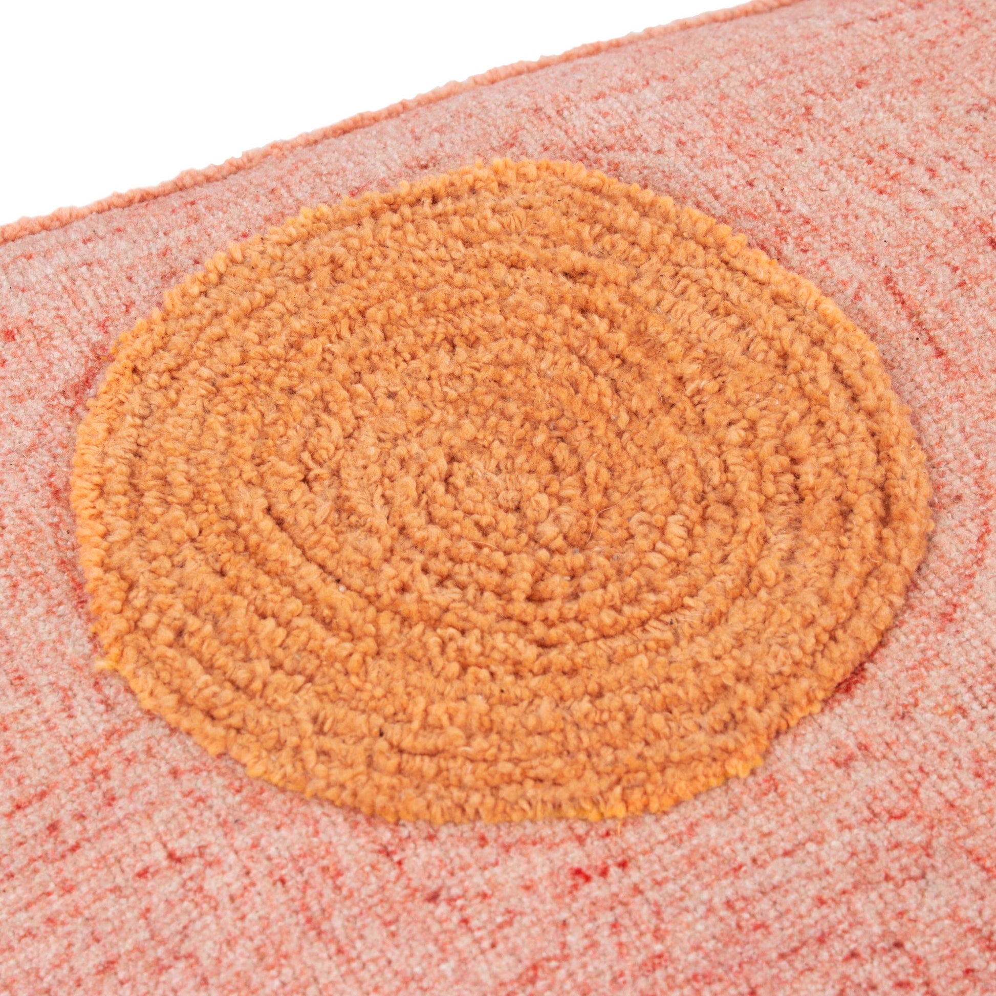 Round doormat with a textured surface on a pink background