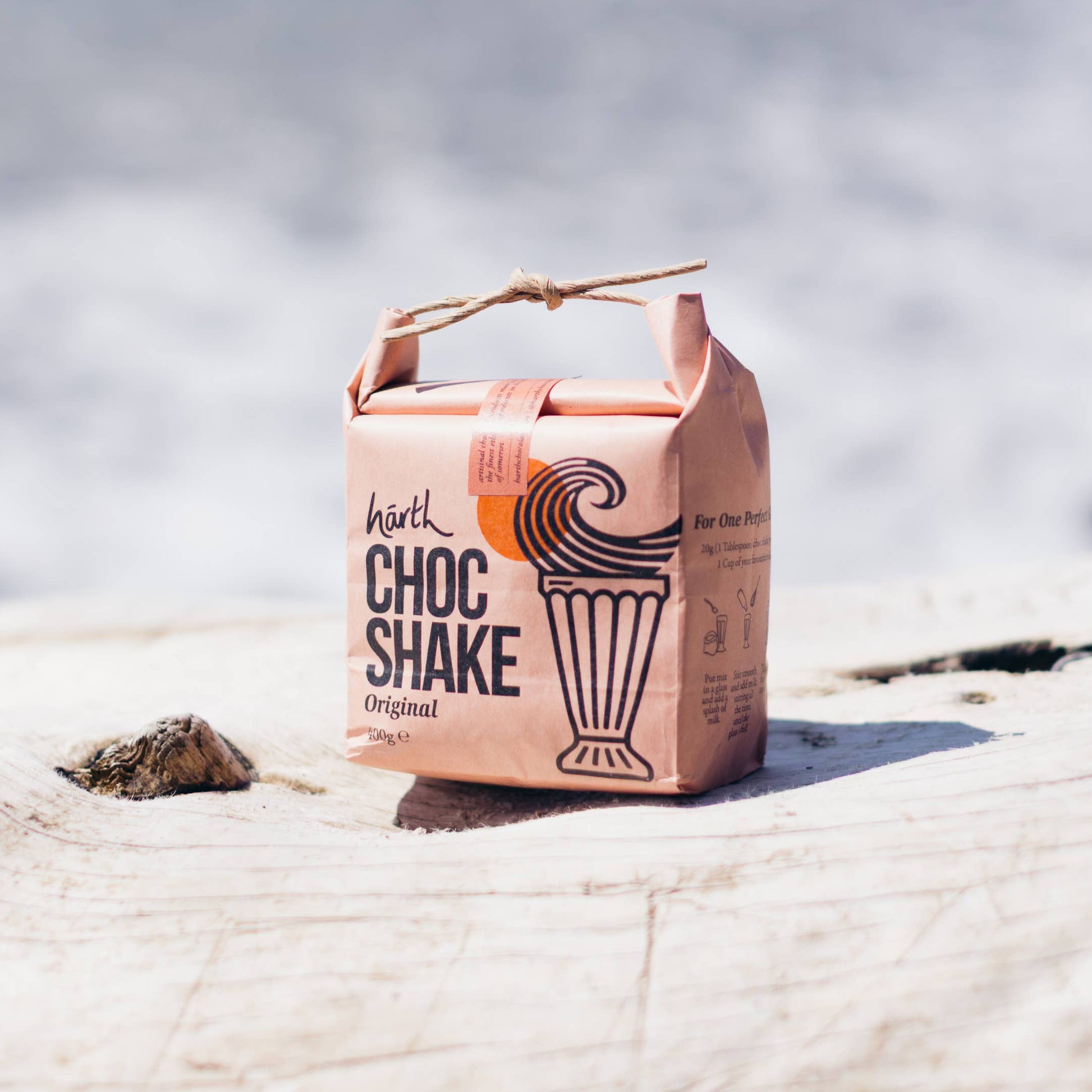 Carton of Choc Shake on a rock with water in the background