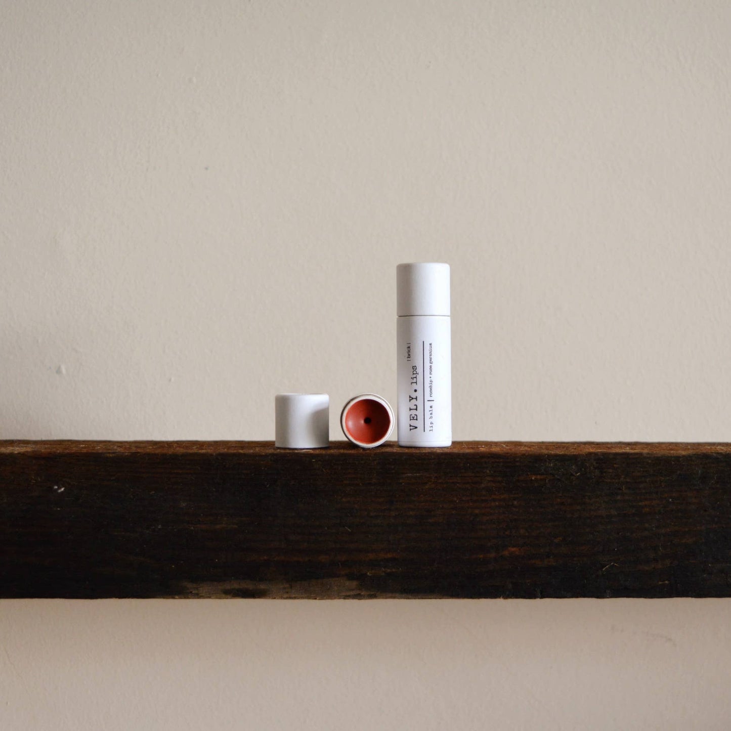 Three cylindrical containers on a wooden shelf against a plain wall