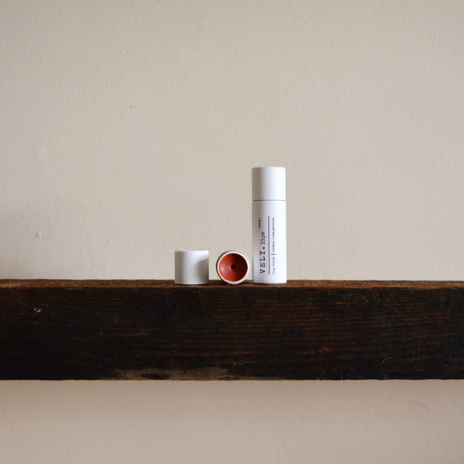 Three cylindrical containers on a wooden shelf against a plain wall