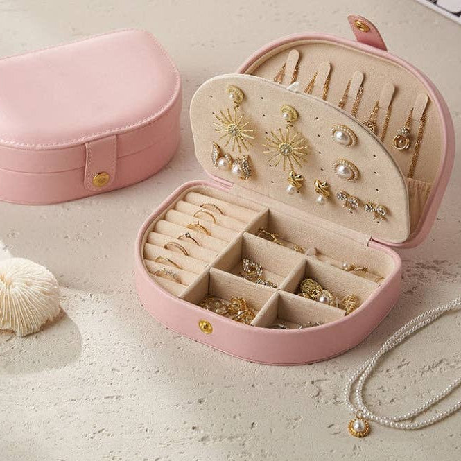 Pink jewelry box with gold earrings on a light surface