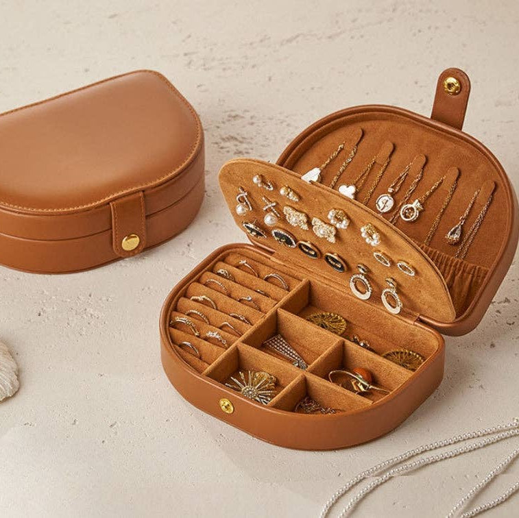 Brown jewelry case with jewelry inside on a beige background