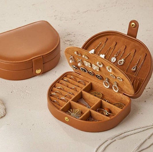 Brown jewelry case with jewelry inside on a beige background