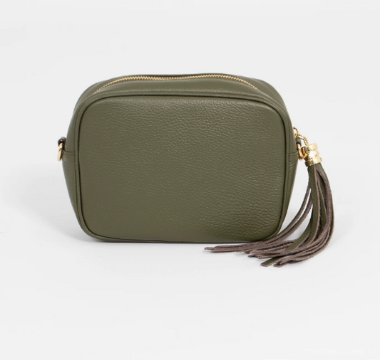 Green leather crossbody bag with a tassel on a light gray background