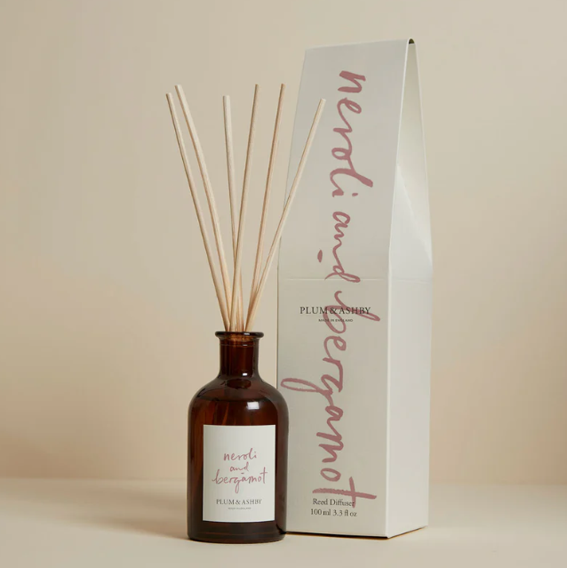 Reed diffuser with packaging on a beige background