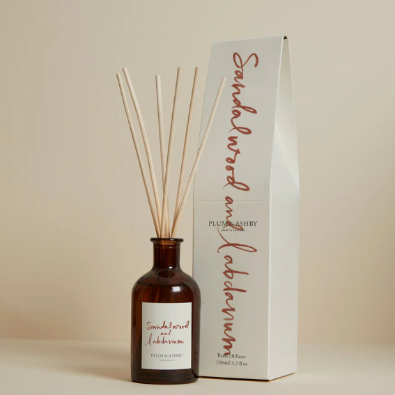 Diffuser bottle with wooden sticks and packaging on a beige background