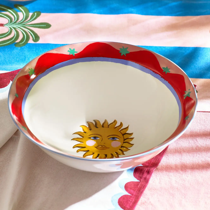 Decorative bowl with sun design on a colorful fabric background