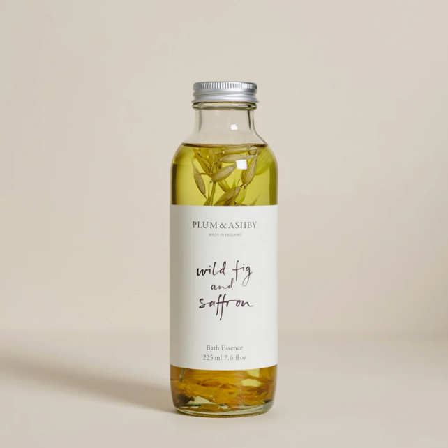 Bottle of Plum & Ashby wild fig and saffron bath essence on a beige background