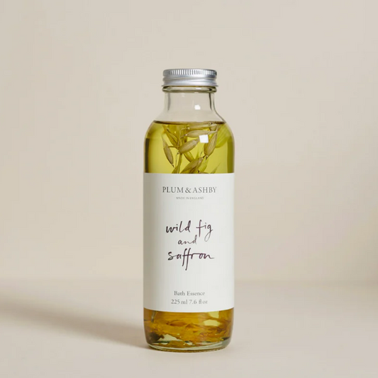 Bottle of Plum & Ashby wild fig and saffron bath essence on a beige background