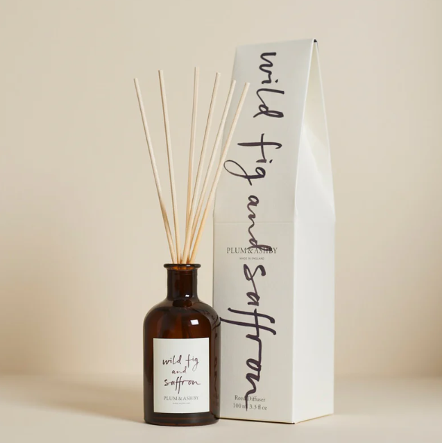 A diffuser bottle with wooden sticks and a matching box on a beige background